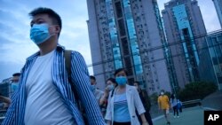 People wearing face masks to protect against COVID-19 walk across a pedestrian bridge near a neighborhood with a suspected coronavirus case in Beijing, Sept. 15, 2021. 