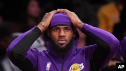 Los Angeles Lakers forward LeBron James sits on the bench during the first half of a preseason NBA basketball game against the Golden State Warriors, Oct. 14, 2019, in Los Angeles.