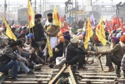 FILE - Farmers block railway tracks during a four-hour rail blockade as they continue their protest against the central government's recent agricultural reforms, at a railway station in Amritsar, India, Feb. 18, 2021.