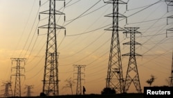 FILE : A man walks beneath electricity pylons during frequent power outages from South African utility Eskom, caused by its ageing coal-fired plants, in Orlando, Soweto, South Africa, January 16, 2023.