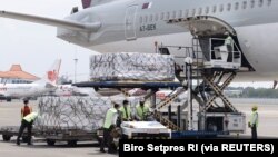 Pekerja mengenakan masker pelindung menurunkan Moderna hasil kerjasama internasional Indonesia-Amerika Serikat melalui fasilitas multilateral COVAX, di terminal kargo Soekarno Hatta International, 11 Juli 2021. (Foto: Courtesy Biro Pers via Reuters)