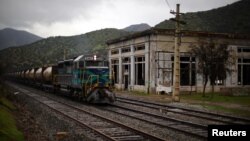 A train transporting garbage rides to a waste dump passing next to an abandoned power plant in Til Til, Chile, Aug. 10, 2017. 