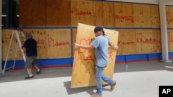 James Redford carries a sheet of plywood as he helps board up windows in preparation for Hurricane Harvey in Corpus Christi, Texas, Aug. 24, 2017. 