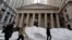 Morning commuters pass snow on Wall Street in front of Federal Hall in New York's Financial District, Jan. 25, 2016.