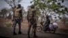 FILE - A police officer and a soldier from Benin stop a motorcyclist at a checkpoint outside Porga, Benin, March 26, 2022.