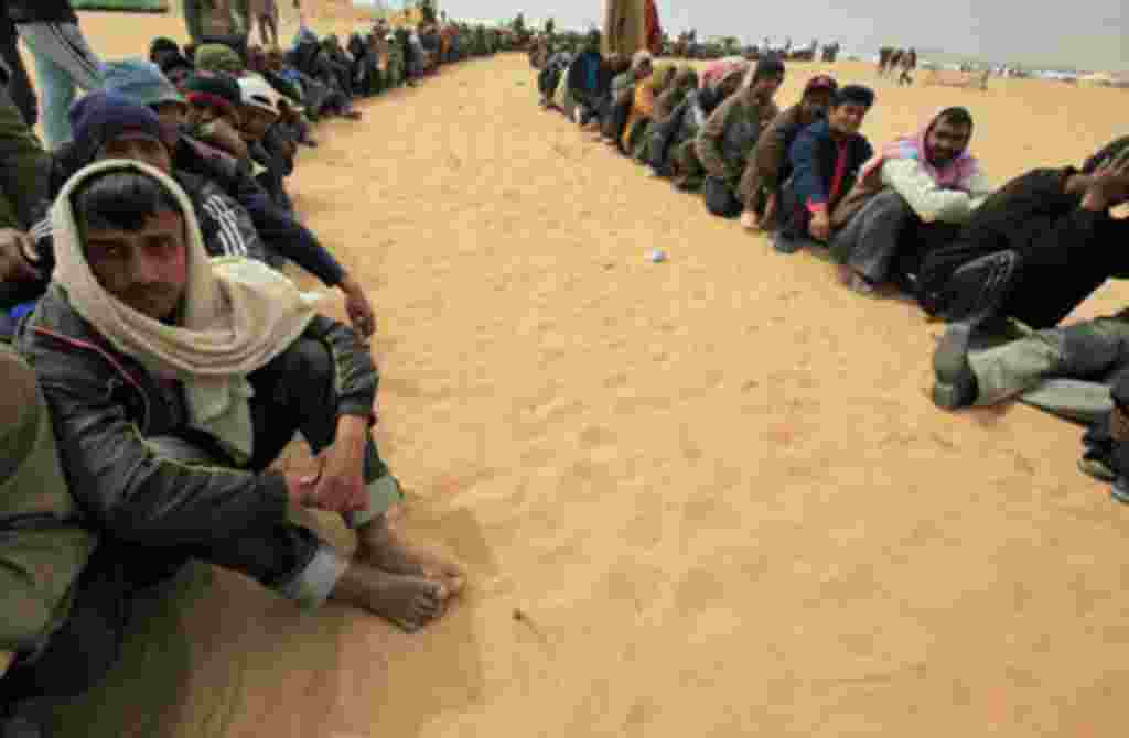 Bangladeshi evacuees wait for food at a refugee camp near the Libyan and Tunisian border crossing of Ras Jdir after fleeing unrest in Libya March 11, 2011