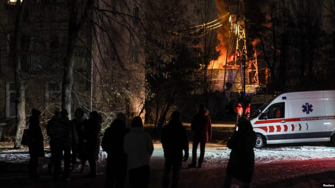 Local residents gather near a residential building as a critical power infrastructure object burns after a Russian drone attack, amid Russia's attack on Ukraine, in Kyiv, Ukraine Dec. 19, 2022. 