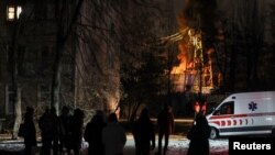 কিয়েভে বৈদ্যুতিক অবকাঠামোর একটি গুরুত্বপূর্ণ স্থাপনা আগুনে পুড়তে থাকার সময়ে সেটির আশেপাশে সমবেত স্থানীয় বাসিন্দা। ১৯ ডিসেম্বর ২০২২।