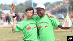 An unidentfied Chinese national and a Zimbabwean man hug while welcoming Chinese President Xi Jinping upon his arrival in Harare, Zimbabwe, Tuesday, Dec. 1. 2015. Jinping is in Zimbabwe for a two day State visit during which he is set to sign some bilateral agreements aimed at strengthening relationships between the two countries. (AP Photo/Tsvangirayi Mukwazhi)