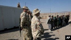 Tentara Australia, bagian dari Pasukan Bantuan Keamanan Internasional (ISAF), berdiri di dekat warga Afghanistan di pangkalan militer Tarin Kowt, Kabul, 17 Februari 2021. (AP/Musadeq Sadeq)