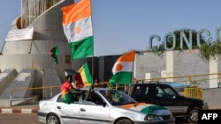 TOPSHOT - Supporters of the Alliance Of Sahel States (AES) drive with flags as they celebrate Mali, Burkina Faso and Niger leaving the Economic Community of West African States (ECOWAS) in Niamey on January 28, 2024. (Photo by HAMA BOUREIMA / AFP)