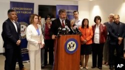 La líder de la minoría de la Cámara de Representantes Nancy Pelosi, demócrata de California (segunda desde la izquierda), observa mientras el representante federal Juan Vargas, demócrata de California, habla en el podio frente a miembros del Caucus hispano del Congreso durante una visita a la frontera, el lunes, 18 de junio de 2018, en San Diego. Los miembros del Congreso hablaron sobre su visita a las instalaciones de detención de inmigración del área. (AP Photo / Gregory Bull).