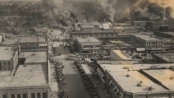 FILE - This photo provided by the Department of Special Collections, McFarlin Library, The University of Tulsa shows crowds of people watching fires during the Tulsa Race Massacre in Tulsa, Oklahoma, June 1, 1921.