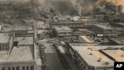 FILE - This photo provided by the Department of Special Collections, McFarlin Library, The University of Tulsa shows crowds of people watching fires during the Tulsa Race Massacre in Tulsa, Oklahoma, June 1, 1921.