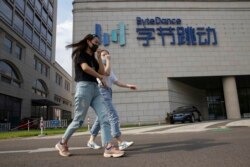 FILE - Women wearing masks to prevent the spread of the coronavirus chat as they pass by the headquarters of ByteDance, owners of TikTok, in Beijing, China, Aug. 7, 2020.