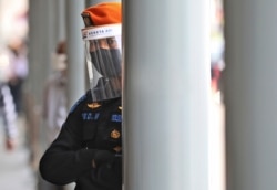 FILE - A security guard wearing protective equipment looks on during a coronavirus test for passengers of long-distance trains at Senen Train Station in Jakarta, Indonesia, July 27, 2020.