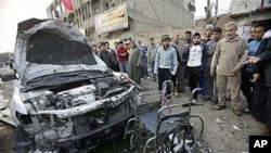 People inspect a destroyed car and a wheelchair at the scene of a car bomb attack that ripped through a funeral tent in a mainly Shiite area in Baghdad, Iraq, January 27, 2011