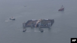 The partially lifted sunken ferry Sewol (center, between two barges) is ready for transportation to a port in waters off Jindo, South Korea, March 24, 2017.