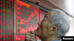 File - An investor watches an electronic board showing stock information at a brokerage office in Beijing, China, July 2015.