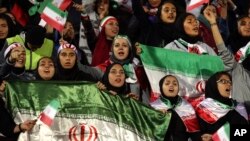 Female Iranian spectators cheer as they wave their country's flag during a friendly soccer match between Iran and Bolivia, at the Azadi (Freedom) stadium, in Tehran, Iran, Oct. 16, 2018.