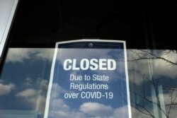 In this Wednesday, April 22, 2020 photo a closed sign is posted in the window of a store because of the coronavirus, in an outdoor mall, in Dedham, Mass. More than 4.4 million laid-off workers applied for U.S. unemployment benefits last week as job…