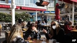 Women chat as they wait to be served at a restaurant reopened for business in Ankara, Turkey, March 2, 2021, as cafes, restaurants and other eateries reopened in some provinces across the country.