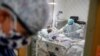 Resident physician Leslie Bottrell stands outside a room at an Intensive Care Unit as a nurse suctions the lungs of a COVID-19 patient, April 20, 2020, at St. Joseph's Hospital in Yonkers, New York.