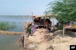 Family members take refuge on a high place after heavy monsoon rains flooded their home near Sohbat Pur, an area of Pakistan's southwestern Balochistan province, on Aug. 19, 2024.