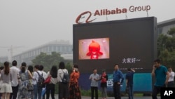 FILE - Visitors walk past a giant display at the Alibaba Group headquarters in Hangzhou, in eastern China's Zhejiang province, May 27, 2016. 