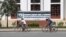 Two cyclists are seen riding past the University of Health Sciences, on 8 August 2015. (Photo: Ouch Nida/VOA Khmer)