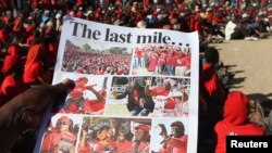 A Zimbabwean opposition party Movement For Democratic Change (MDC) supporter holds a party newsletter at an election rally, about 90 km (56 miles) east of the capital Harare, July 23, 2013.