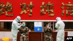 FILE - This photo taken Feb. 11, 2020, shows medical staff members (R) collecting samples from Chinese paramilitary police officer to be tested for the COVID-19 coronavirus as they return from holidays in Shenzhen in China's southern Guangdong province.