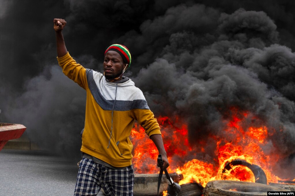 Um manifestante em frente a pneus queimados na manifesta&#231;&#227;o contra o governo em Luanda. A pol&#237;cia anti-motim, alguns montados em cavalos, disparou g&#225;s lacrimog&#233;neo e agrediu dezenas de manifestantes. 24 outubro 2020