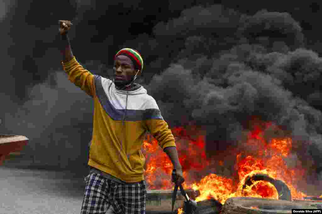 Um manifestante em frente a pneus queimados na manifesta&#231;&#227;o contra o governo em Luanda. A pol&#237;cia anti-motim, alguns montados em cavalos, disparou g&#225;s lacrimog&#233;neo e agrediu dezenas de manifestantes. 24 outubro 2020