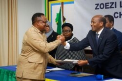 The opposition Chadema party's Tundu Lissu, left, hands over his electoral nomination form to election chairman Semistocles Kaijage, right, in Dodoma, Tanzania, Aug. 25, 2020.