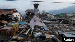 A teddy bear hangs next to earthquake and tsunami damaged property along the waterfront in Palu, Central Sulawesi, Indonesia, Oct. 10, 2018.