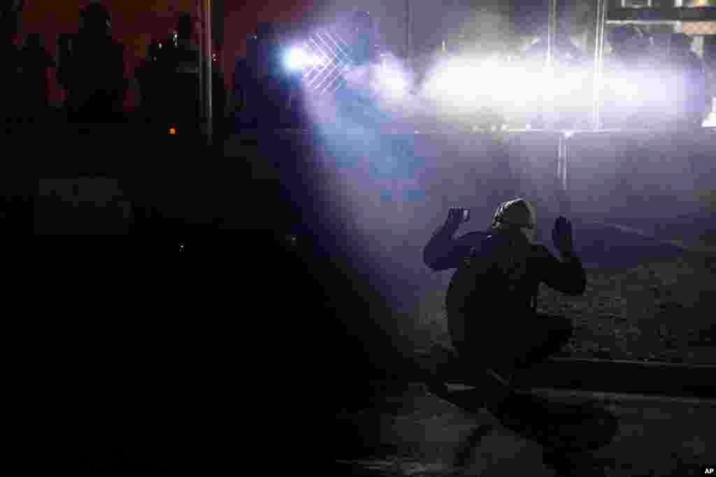 Police shine lights on demonstrator with raised hands during a protest over Sunday&#39;s fatal shooting of Daunte Wright during a traffic stop, outside the Brooklyn Center Police Department in Brooklyn Center, Minnesota.