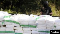 FILE - A police officer stands guard behind rows of confiscated drugs inside a military base in Santo Domingo.