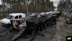 疏散平民的车辆驶经基辅近郊被摧毁的俄罗斯坦克车(2022年3月9日）