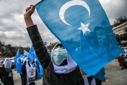 FILE - Female members of the Muslim Uyghur minority chant slogans and wave flags of East Turkestan as they demonstrate to ask for news of their relatives near China's consulate in Istanbul on March 8, 2021.