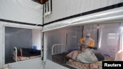 FILE - Moise Vaghemi, an Ebola survivor who works as a nurse, tends to a suspected Ebola sufferer inside the Biosecure Emergency Care Unit at an Ebola treatment center in Katwa, DRC, Oct. 3, 2019.