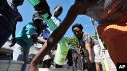 Haitian earthquake victims struggle to get water from a distribution team in Port-au-Prince on 18 Jan 2010