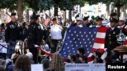 A New York police bagpipe team plays as they stand with an American flag from the World Trade Center during a ceremony marking the 20th anniversary of the September 11, 2001 attacks in New York City, Sept. 11, 2021.