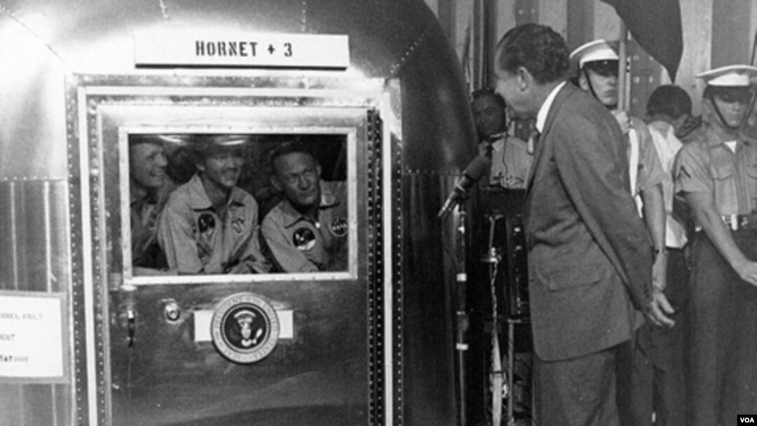 El presidente Richard M. Nixon habla con los astronautas del Apolo 11, Neil Armstrong, Michael Collins y Edwin Aldrin. Los astronautas se encuentran dentro de la estación móvil en cuarentena tempora después de su regreso a la Luna.