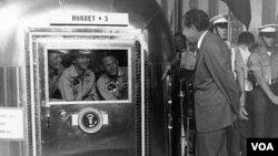 El presidente Richard M. Nixon habla con los astronautas del Apolo 11, Neil Armstrong, Michael Collins y Edwin Aldrin. Los astronautas se encuentran dentro de la estación móvil en cuarentena tempora después de su regreso a la Luna.