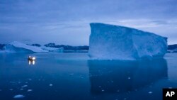 FILE: A boat navigates at night next to large icebergs in eastern Greenland on Aug. 15, 2019. Zombie ice from the massive Greenland ice sheet will eventually raise global sea level by at least 27 centimeters on its own, according to a study released Monday, Aug. 29, 2022.