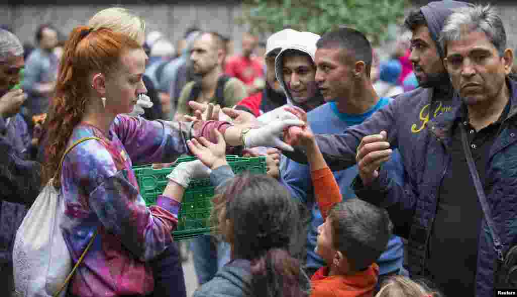 A helper distributes fruit to migrants in front of the State Office for Health and Social Affairs (LaGeSo), in Berlin, Germany, Sept. 3, 2015.