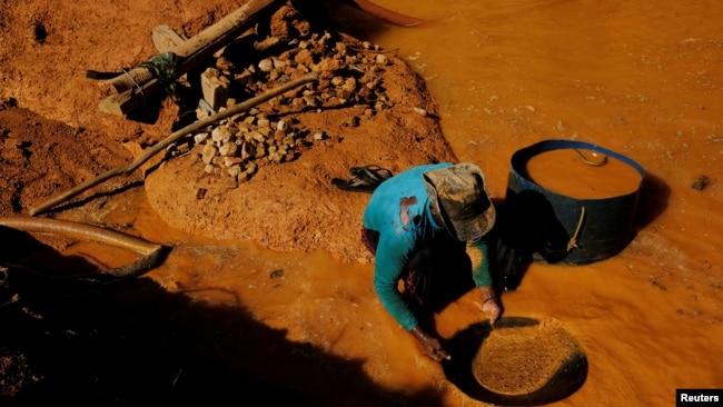 FILE - A wildcat gold miner, or garimpeiro, uses a tool and mercury to search for gold at a wildcat gold mine, also known as a garimpo, at a deforested area of the Amazon rainforest near Crepurizao, Para State, Brazil, August 5, 2017. (REUTERS/Nacho Doce/File Photo)