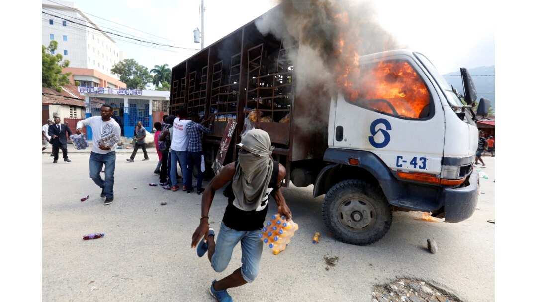 Demonstrators loot a burning truck after the wake of demonstrators killed during the protests to demand the resignation of Haitian president Jovenel Moise in Port-Au-Prince, Haiti, Nov. 19, 2019.