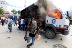 Demonstrators loot a burning truck after the wake of demonstrators killed during the protests to demand the resignation of Haitian president Jovenel Moise in Port-Au-Prince, Haiti, Nov. 19, 2019.